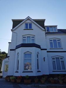 a white house with blue windows and potted plants at Coombe Lodge Holiday Flats in Paignton