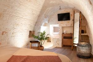 a bedroom with a bed and a tv in a stone wall at Monte Adamello - dimora nei trulli in Alberobello