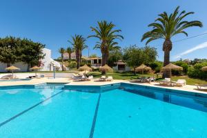 a large swimming pool with chairs and palm trees at Parque Monte Verde in Albufeira