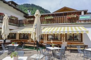 a patio with tables and umbrellas in front of a building at Gasthof Albergo Neuwirt in Val di Vizze