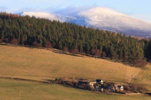 an aerial view of a field with a snow covered mountain at Easter Corrie Cottages in Ballindalloch