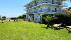 a large white building with hammocks in a yard at Maritsa's Rooms in Stavros