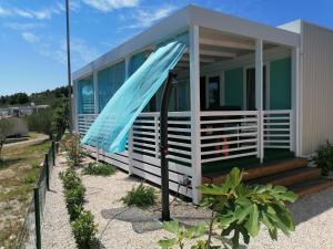 een klein huis met een blauwe paraplu ervoor bij White-Pearl Mobile-Home in Jezera