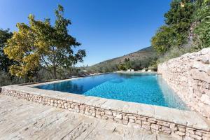uma piscina com uma parede de pedra ao lado de uma parede de pedra em Villa della Genga Country Houses em Poreta