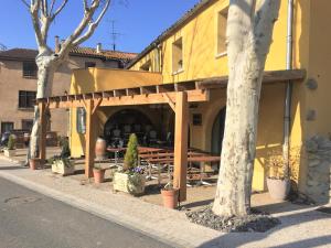 a yellow building with a table and trees on a street at La Maison Des Vendangeurs in Villesèque-des-Corbières