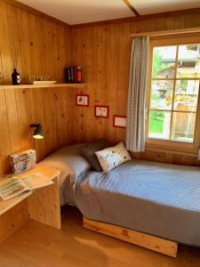 a bedroom with a bed and a desk and a window at Chalet Butterfly in Adelboden