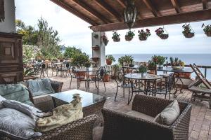 an outdoor patio with tables and chairs and the ocean at villa antica in Ischia