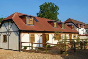 a white house with a red roof and a fence at Shepherds Spring Cottages in Ringwood