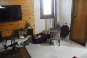 a living room with a fireplace and a tv at Aconchego da Serra Edícula in São Joaquim