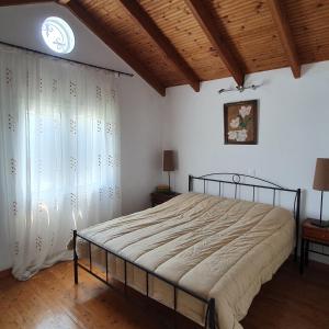 1 dormitorio con 1 cama y ventana con reloj en Σγουρής (Sgouris), en Lefkimmi