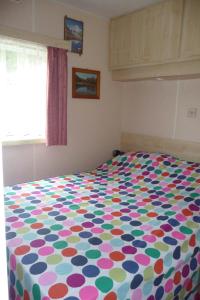 ein Bett mit farbenfroher Bettdecke in einem Schlafzimmer in der Unterkunft Altogold Swiss Holidays At Manor Farm 5* in Interlaken