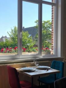 a table in a restaurant with two windows at A La Villa Perroy les chambres sont spacieuses et les petit-déjeuners offerts in Dunkerque