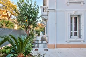 a white building with a gate and a tree at Villa Angelus in Nice