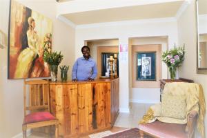 a man standing behind a wooden podium in a room at Florentia Guest House in Bloemfontein