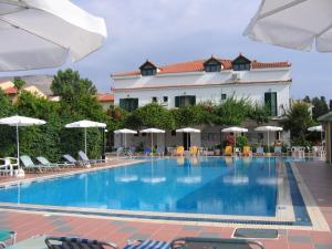 a pool with chairs and umbrellas in front of a hotel at Tara Beach Hotel in Skala Kefalonias