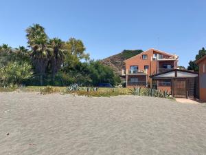 a sandy beach with a house in the background at apartamento playa privada in Torre del Mar