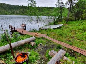 a dog sitting on a wooden dock next to a boat at Kotomänty Apartments in Ruka