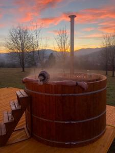 a wooden hot tub on a wooden deck with a sunset at Holiday Homes Vita Natura in Rakovica