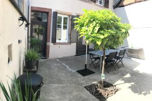 a patio with a table and chairs and a tree at BELISAMA in Molsheim
