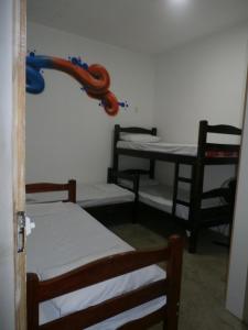 a room with three beds and a table and chairs at Balcony Hostel Hotel in Sao Paulo