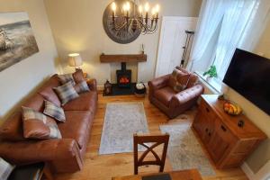 a living room with leather couches and a fireplace at Smart & Stylish Holiday Apartment in the city centre in Inverness