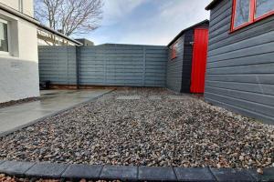 a garage with a red door and a pile of rocks at Smart & Stylish Holiday Apartment in the city centre in Inverness
