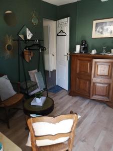 sala de estar con paredes verdes, silla y mesa en La Cour Du Puits chambre Maxime, en Cormeilles