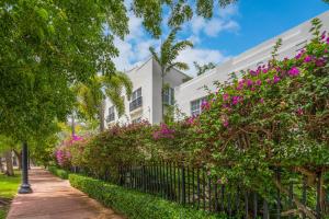 ein weißes Gebäude mit rosa Blumen und einem Zaun in der Unterkunft Fountain condo 2 story Pool BBQ Balcony in Miami Beach