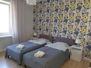 a bedroom with two beds and a wall with a wallpaper at Apartament Blisko Morza Gdynia in Gdynia