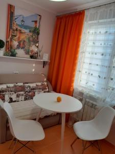 Una mesa blanca y dos sillas frente a una ventana. en НОВАЯ КРАСИВАЯ квартира., en Cherkasy