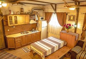 cocina con armarios de madera, fregadero y nevera en Usadba Belovezhskoye Pomestye, en Kamenyuky