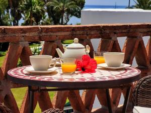 a table with a teapot and two glasses of orange juice at Spacious Beachfront Town House in Estepona with Fully Equipped Kitchen, Pools, Garden, Sea View in Estepona