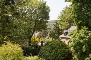 un patio con árboles y una casa con una colina al fondo en Au Souffle de Vert en Bouvaincourt-sur-Bresle