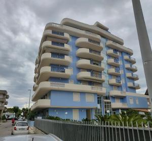 a blue apartment building with cars parked in front of it at RICCIO BLU pochi passi dal mare in Alba Adriatica