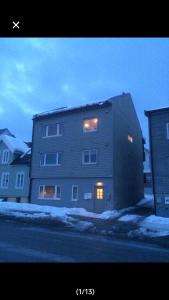 um grande edifício de terra com as suas luzes acesas na neve em Studio1 em Tromsø