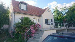 een huis met een trap en een balkon met roze bloemen bij Villa spacieuse lumineuse à Paris in Argenteuil