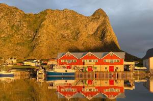 a red house and a boat in a body of water at Bensvik Brygge in Værøy