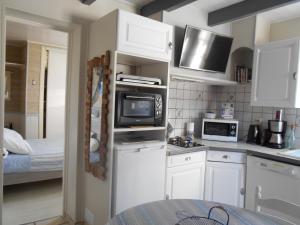 a kitchen with white cabinets and a microwave at ILE DE RE, LA DANAE avec VELOS, WIFI, COIN CUISINE, LINGE, PARKING gratuit in Saint-Martin-de-Ré