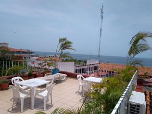 a patio with tables and chairs and the ocean at Casa Kraken Hostel in Puerto Vallarta