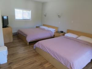 a room with two beds and a flat screen tv at Qualicum Bay Resort in Bowser
