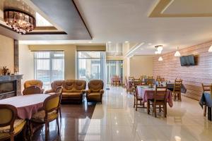 une salle à manger avec des tables, des chaises et une télévision dans l'établissement Nikolaevskiy Guest House, à Kabardinka