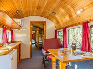 uma cozinha e sala de jantar de um comboio com tecto de madeira em Ohakune Train Stay - Carriage B em Ohakune