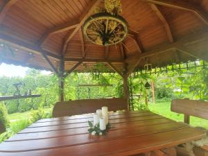 a wooden table in a gazebo with a clock at Gospodarstwo Agroturystyczne Borówkowy Bukiet Smaków in Iwkowa