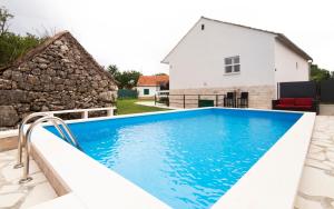 ein Schwimmbad mit einem Haus im Hintergrund in der Unterkunft Holiday Home Relax in Neorić