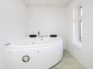 a white bathroom with a toilet and a window at 20 person holiday home in Ulfborg in Husby