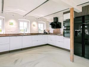 a kitchen with white cabinets and black appliances at 20 person holiday home in Ulfborg in Husby