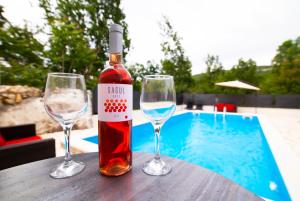 een fles wijn zittend op een tafel met twee wijnglazen bij Holiday Home Relax in Neorić