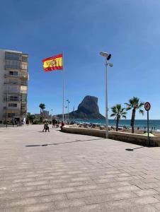a flag flying over a beach with a mountain in the background at Appartement de Jerry in Calpe