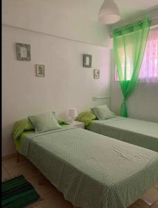 a bedroom with two beds with green sheets and a window at Appartement de Jerry in Calpe
