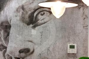een muur met een schilderij van een gezicht erop bij Mamo Florence - Ricasoli Apartment in Florence